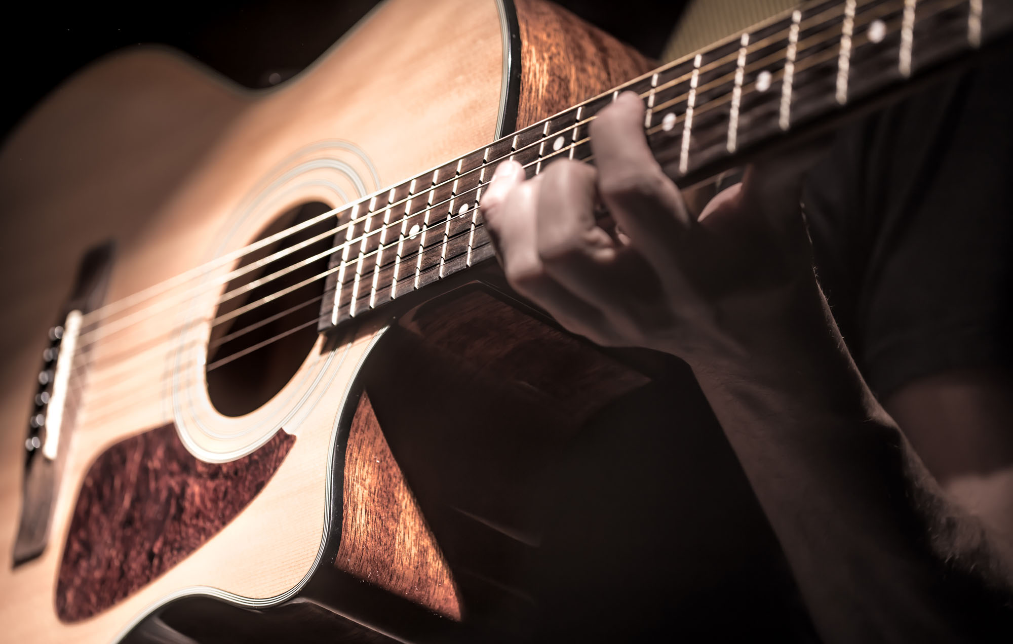 Man playing acoustic guitar on dark background. A musical concept.